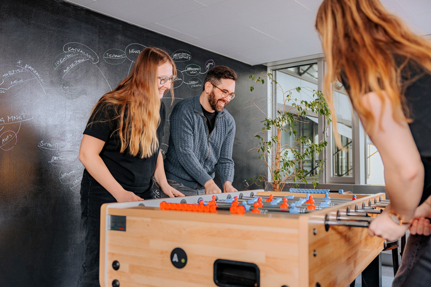 Vier Personen spielen Tischfussball.