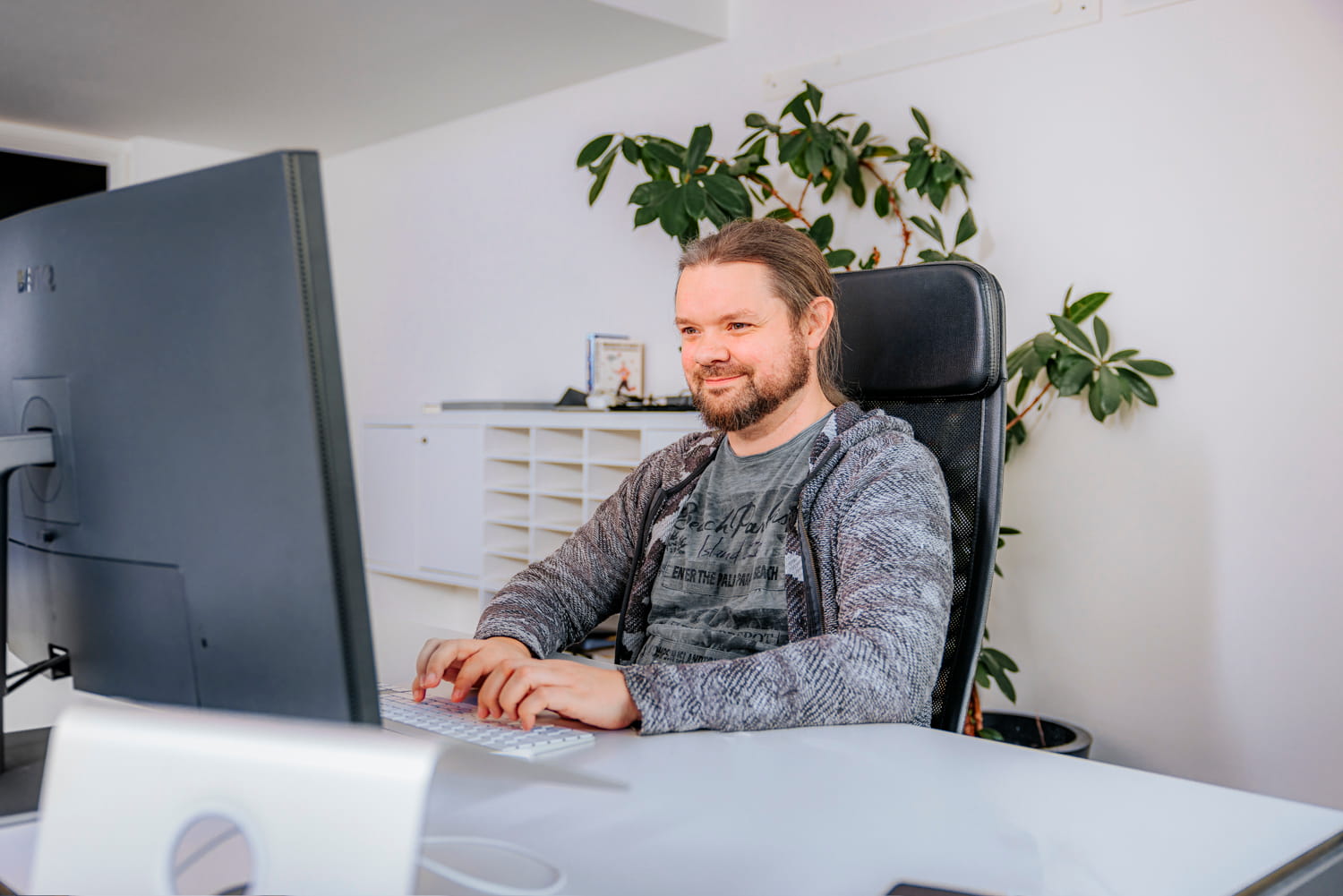 Eine Person sitzt am Schreibtisch vor dem Laptop