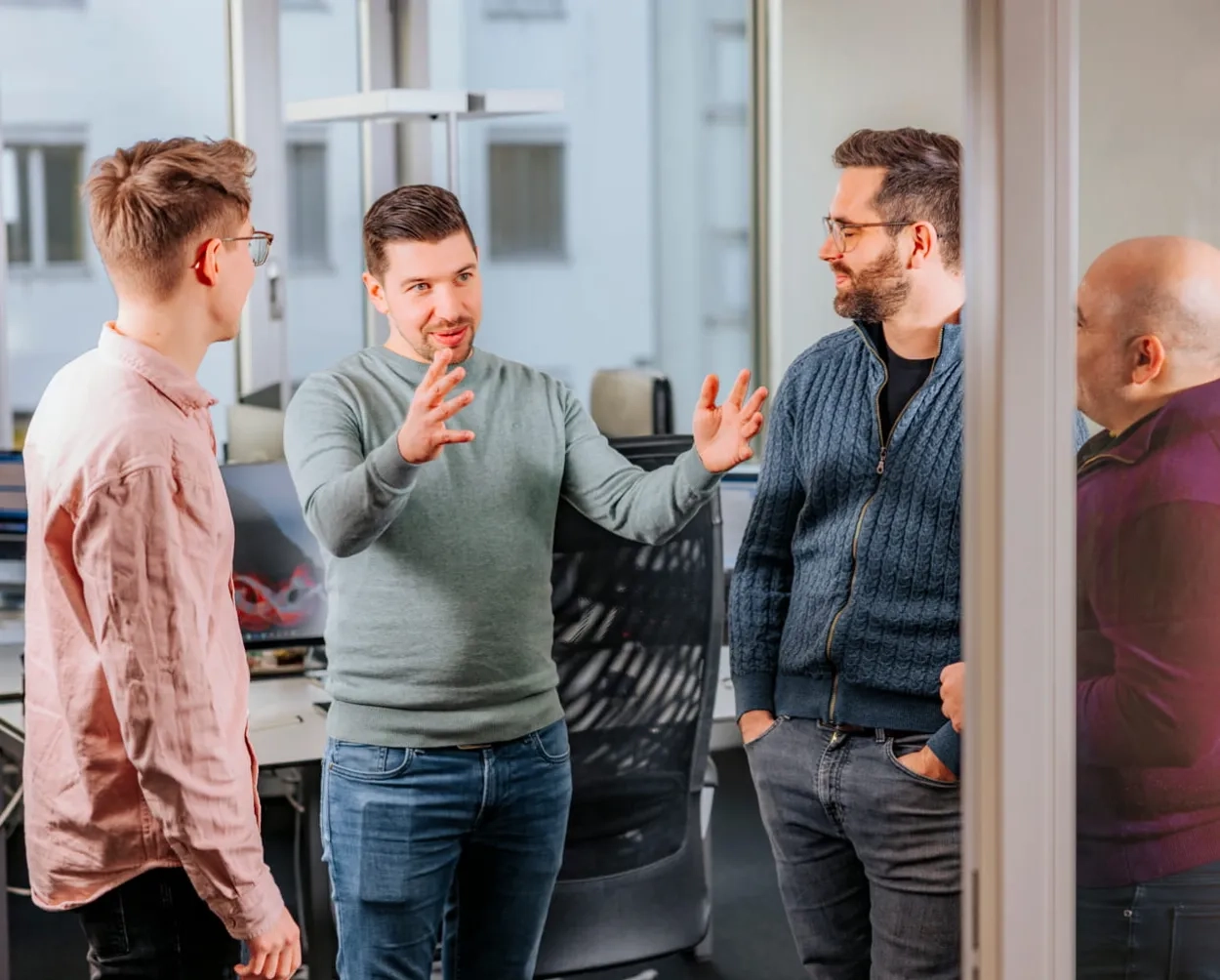 Vier Männer diskutieren miteinander im Stehen.