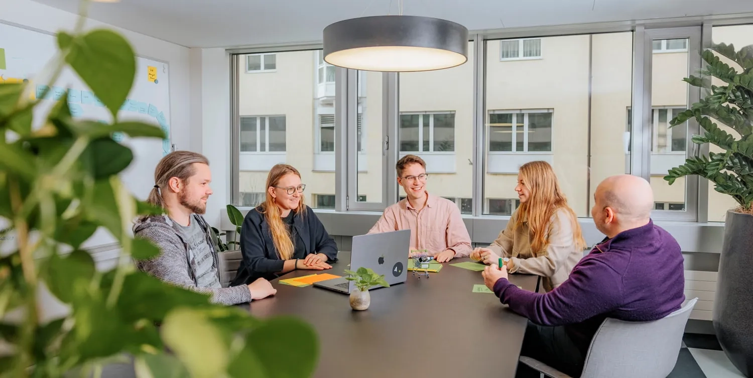 Eine Gruppe von Menschen sitzt an einem Meeting Tisch