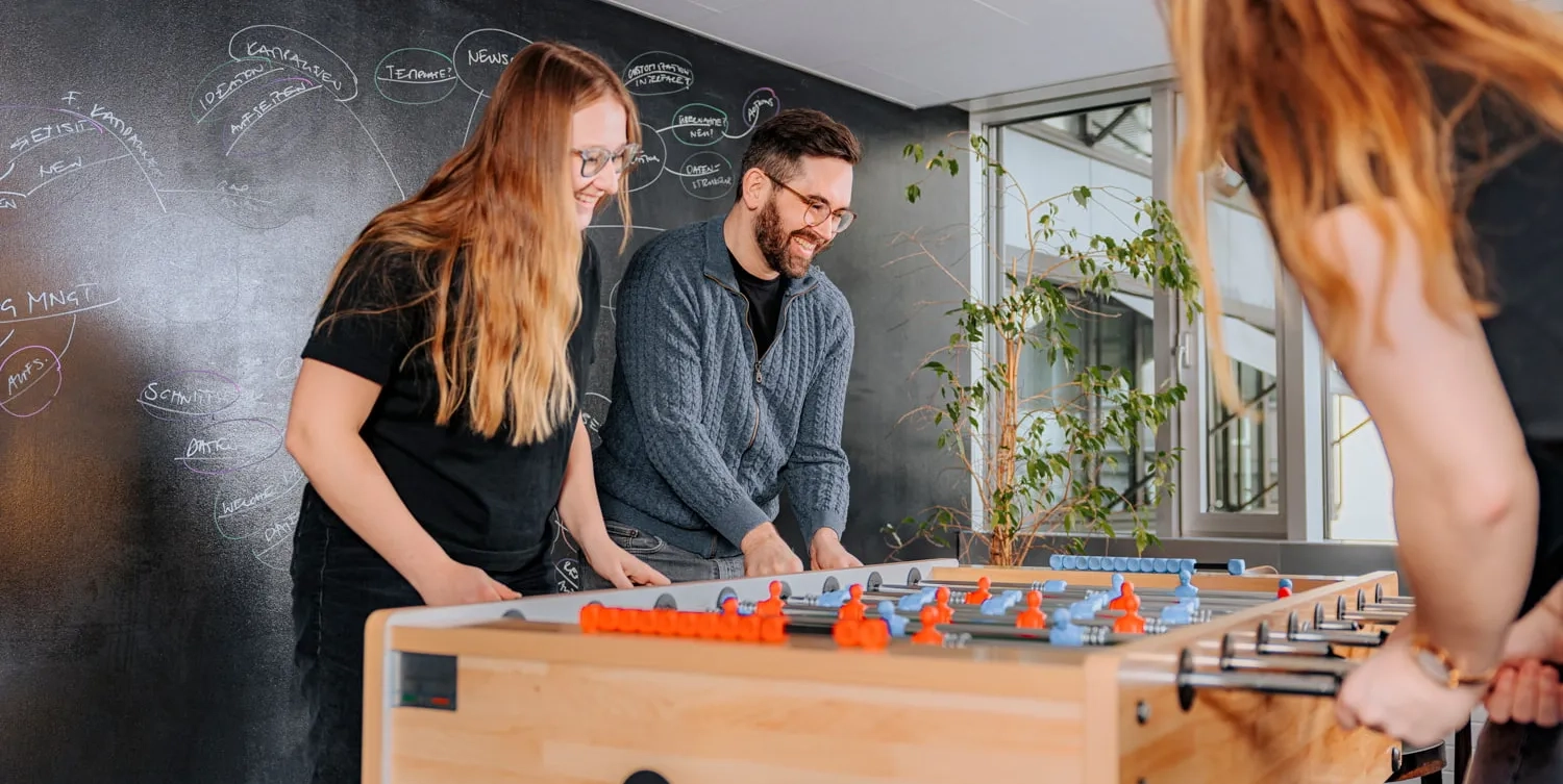 Vier Personen spielen Tischfussball.