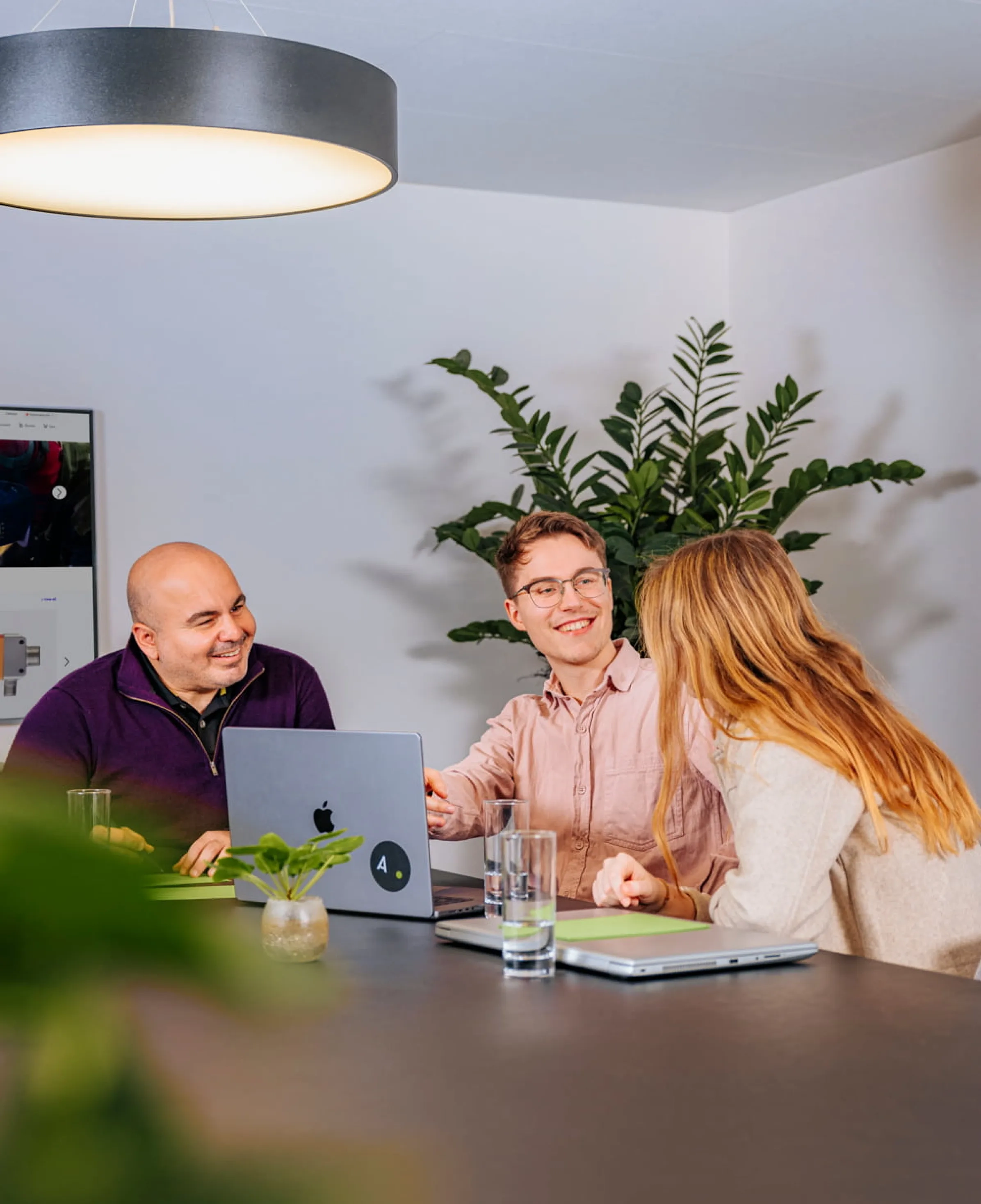 Drei Personen sitzen an einem Tisch und diskutieren.